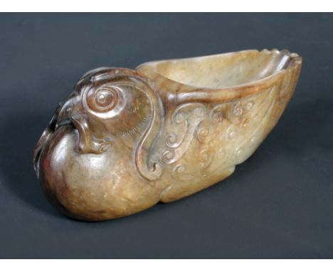 A late 18th/early 19th century jade libation cup, the pale green stone with areas of brown crust, carved as a bird with lingz