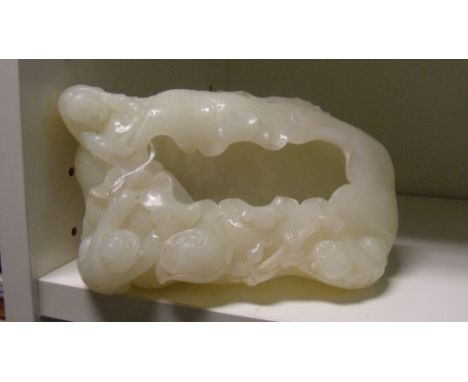 A white jade brush washer carved with three boys clinging to the curled edge of a lotus leaf, one holding the stem to a seed 