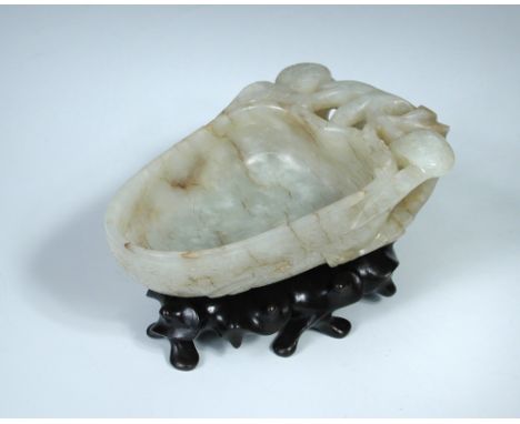 An 18th century nephrite jade libation cup with wood stand, the brown streaked pale green stone bowl of acorn shaped outline 