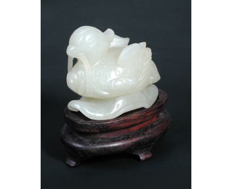 A white jade mandarin duck, possibly late Ming, the bird with upswept wings with lotus in its beak, the supporting leaf pierc