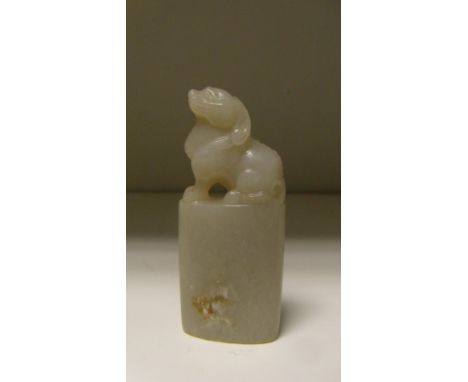 A green mottled white jade uncut seal, the handle carved as a long horned beast with paw feet above an oval sectioned body, 8