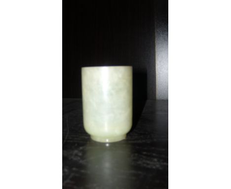 A pale green jade beaker, the cylindrical sides rounding to the foot, 7cm (2.75 in) high  