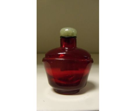 A ruby glass snuff bottle with green agate stopper, rounded shoulders rising out of the flattened bowl shape, 6.5cm (2.5 in) 