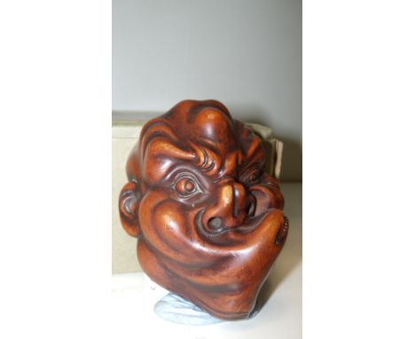 A 19th century wooden mask netsuke, possibly of Hiottoku, the man contorting his lips up towards his left cheek, 8.5cm (3.25 
