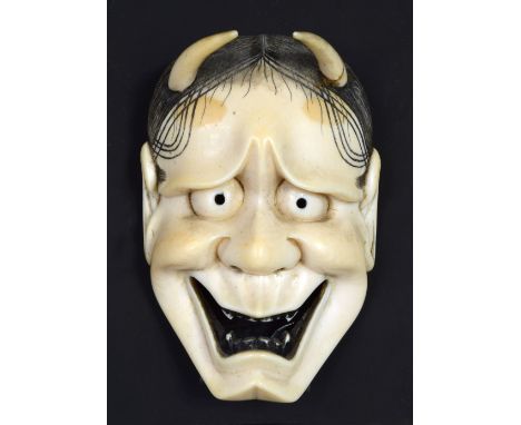 An ivory mask netsuke of Hannya, signed Tamatoshi, the horned face smiling devilishly, his teeth and hair picked out in black