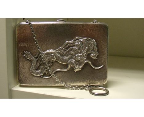 An early 20th century silver purse/card case, the hinged hammered rectangular shape with a dragon in relief on one side, the 