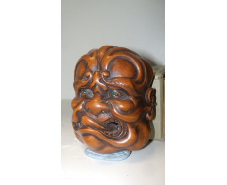 A wooden mask netsuke, signed Nobuaki, the grimacing man with his tongue tip raised out of his mouth towards his right cheek,