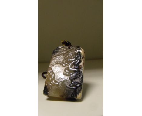 A jade rectangular pendant carved on one side with a dragon rising to one side of a sage, black and white edging to one side 