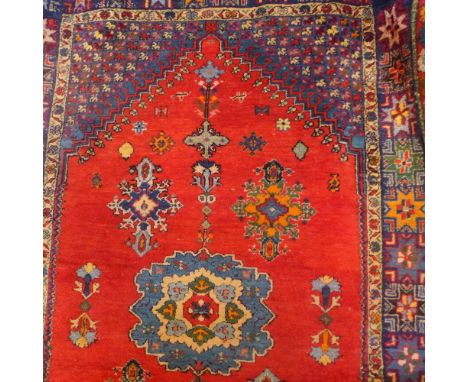 A Moroccan red ground carpet with central medallion contained by borders. 255cm X 164cm 