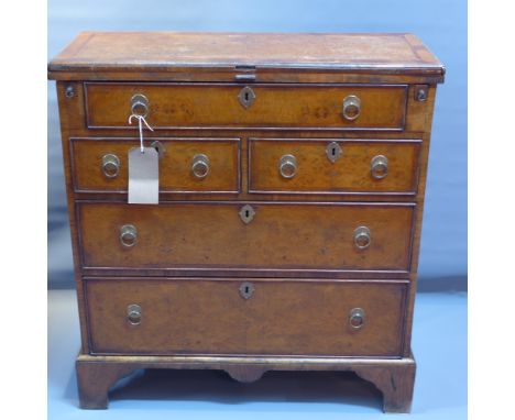 A Georgian walnut batchelors chest with fold over desk above an arrangement of five drawers and raised on carved bracket feet