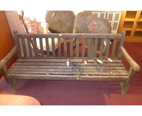 A weathered teak three seater garden bench. H-82cm W-183cm D-62cm