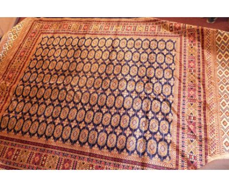 A Bokhara style carpet with elephant pad motifs on a blue ground contained by borders. 280cm X 200cm