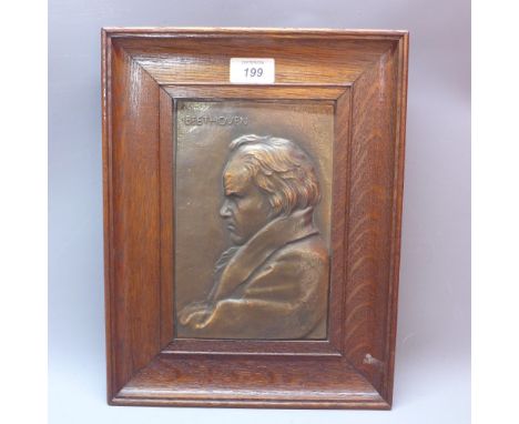 An embossed copper plaque depicting a portrait of Beethoven in oak frame.