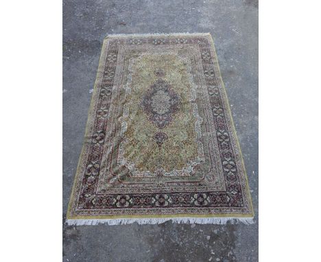 A large Indian silk carpet, central tear drop medallion over olive and spandrel ground, indigo border, 310x184