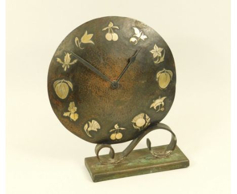 MANTEL CLOCK.A planished copper & wrought iron mantel clock with applied brass flowers & fruit 'numerals'. (Replacement batte