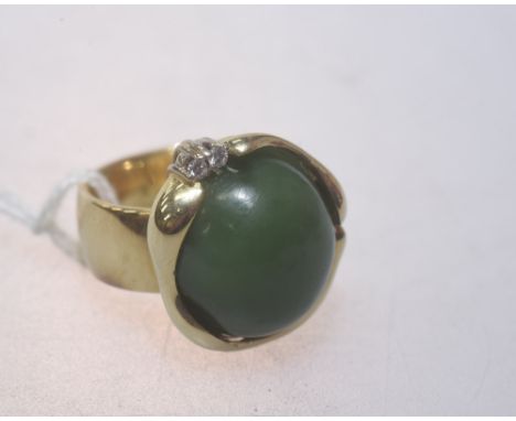 A gold ring set with an imposing jade cabochon, the mount set with two diamonds, (unmarked but tests as gold). Size S