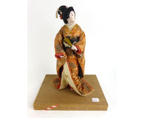 A large Japanese ceramic doll of Geisha girl on wooden plinth together with a doll and toy world magazine 1987 depicting vari