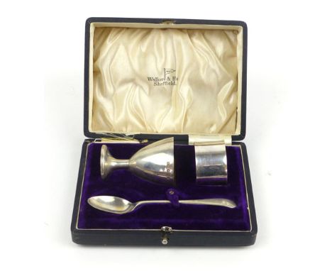 A cased silver christening set including an egg cup, napkin ring and feeding spoon, makers Walker & Hall, Sheffield, 1916, we