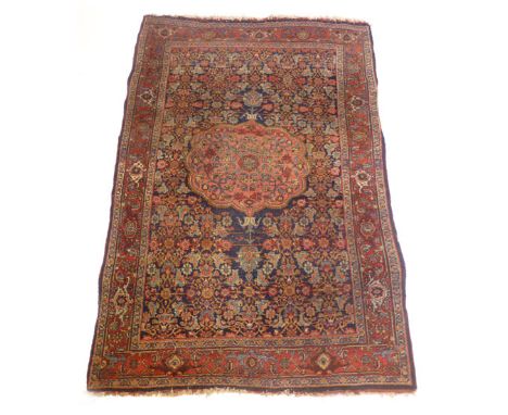 A Persian carpet with a central floral medallion on a blue and red ground with scrolling stylized floral design,  135 x 200 c