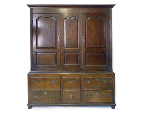 An 18th century and later livery cupboard, a pair of shaped panel doors flanking a central panel on a base with an arrangemen