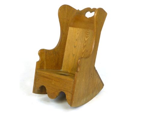 A child's oak rocking wing backed chair with heart shaped cut out back and commode seat  CONDITION REPORT: Surface scratching