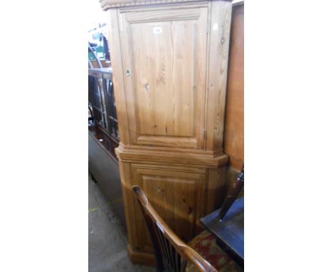 A 20th Century two part pitch pine corner cupboard, the upper cupboard with dentil cornice, each part enclosed by panel doors