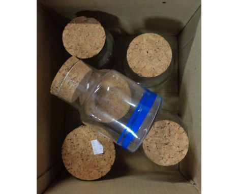 A box containing six vintage glass kitchen storage jars with cork tops