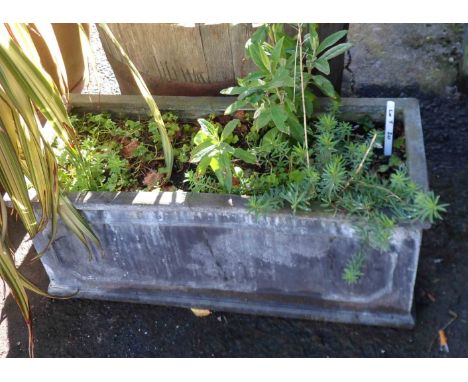 An oblong composite material planter of classical form with assorted garden plants