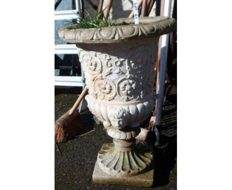 A concrete garden planter of classical urn form with floral decoration and mask head bosses