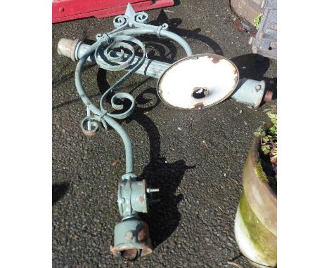 An old outside electric lamp with cast iron pillar and wrought iron bracket with scrolling decoration and enamel shade