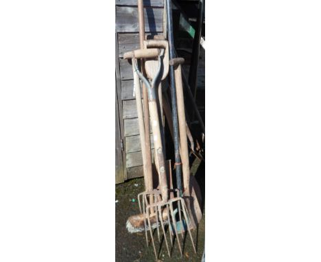 A selection of old garden tools including spades, forks, brush, etc.
