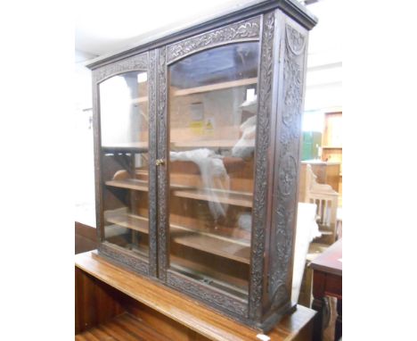 A 69cm early 20th Century wall mounted display cabinet with all round carved oak leaf decoration and battened shelves enclose