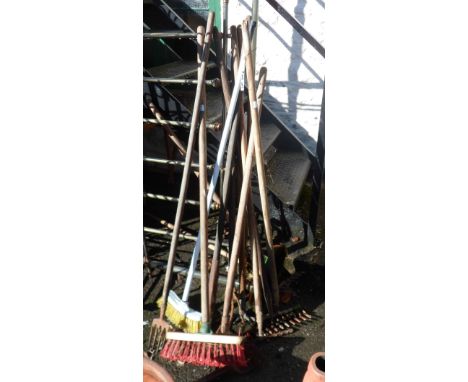 A quantity of old garden and other tools including rakes, brushes, forks, etc.