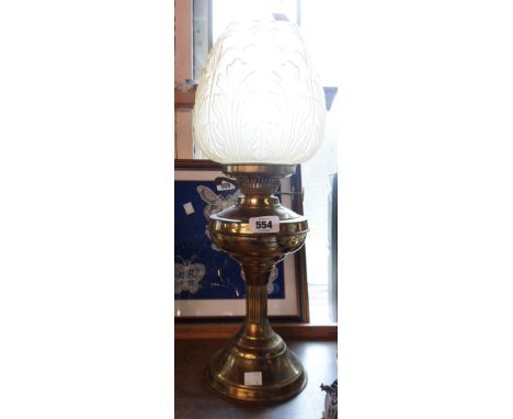 An old brass oil lamp with glass chimney and moulded amber glass shade with floral panel decoration