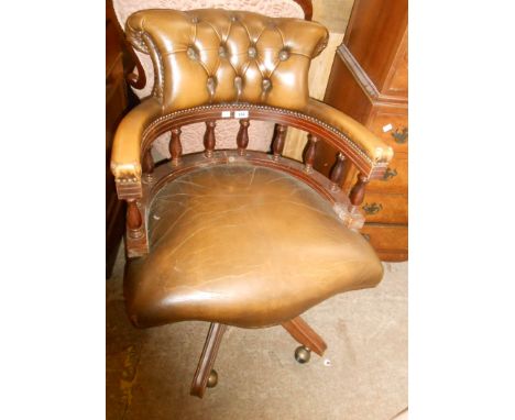 A reproduction captain's chair with studded button back upholstery, set on quintuple splayed legs and casters - wear to arm r