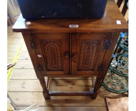 A 49cm 20th Century oak cabinet enclosed by a pair of decorative carved panel doors, set on turned supports