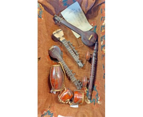 A wooden tray containing a set of antique Indian handmade miniature musical instruments including sitar, drums, etc.