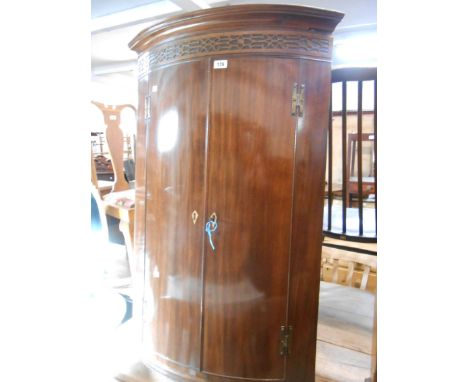 A 72 cm antique mahogany wall hanging bow front corner cabinet with blind fretwork decoration to top and shelves enclosed by 