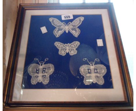 A framed and glazed panel containing four hand worked lace butterflies