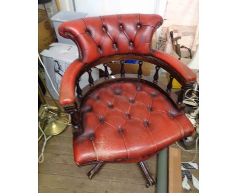 A reproduction stained wood framed captain's chair with red button back leather upholstery, set on five swept legs and caster