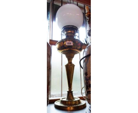 A late 19th Century cast brass oil lamp of column form with brass reservoir, later burner and chimney and associated opaque g