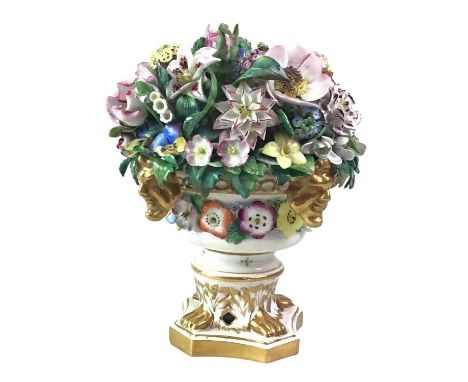 DERBY POSY MODEL, 19TH CENTURY  richly modelled with flower heads and leaves in a circular urn with mask motifs and square ba