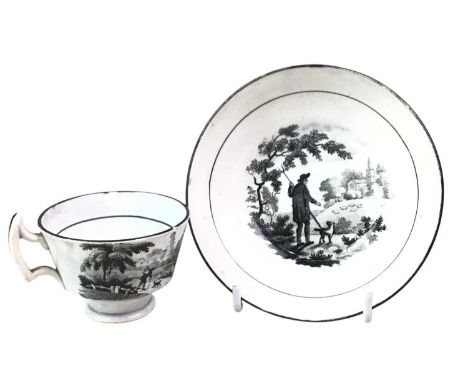 TWO BLACK AND WHITE CUPS AND SAUCERS, of miniature form, decorated in black and white pastoral scenes, with black piping edge