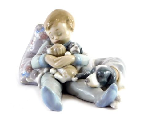 A Lladro figure of a sleeping child, holding puppies aside dog, number 1535, printed and impressed marks beneath, 18cm wide. 