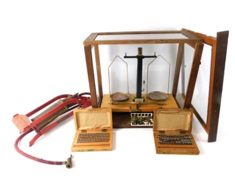 An early 20thC laboratory scales, in glazed dome with metal pans, 41cm high, 46cm wide, 26cm deep, a foot pump, and a cased s