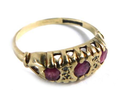 A 9ct gold gypsy ring, set with three rubies in rub over setting, with four tiny diamonds and scroll design shoulders, ring s