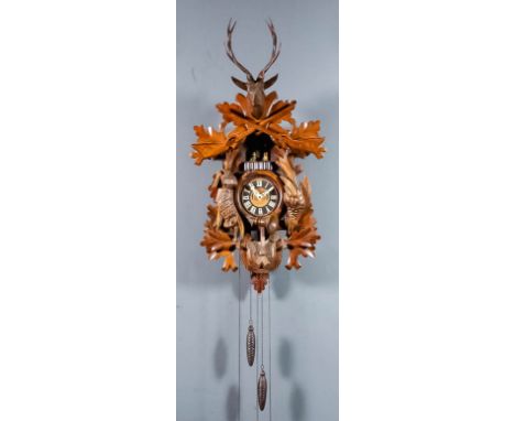 A German stained and carved wood "Cuckoo" clock, the 4.5ins diameter ebonised dial with applied resin Roman numerals to the 3