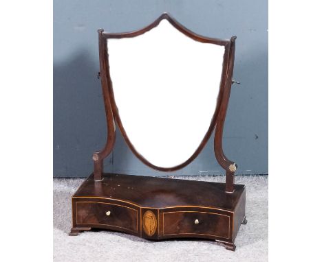 A George III mahogany framed shield shaped toilet mirror on shaped uprights, the shaped base crossbanded and inlaid with oval