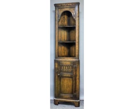 A Titchmarsh & Goodwin oak two-tier corner cupboard of "17th Century" design, the upper part with moulded and carved cornice,