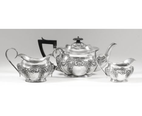 An Edward VII silver three piece tea service of rectangular lobed form, embossed with C-scroll and floral ornament, comprisin